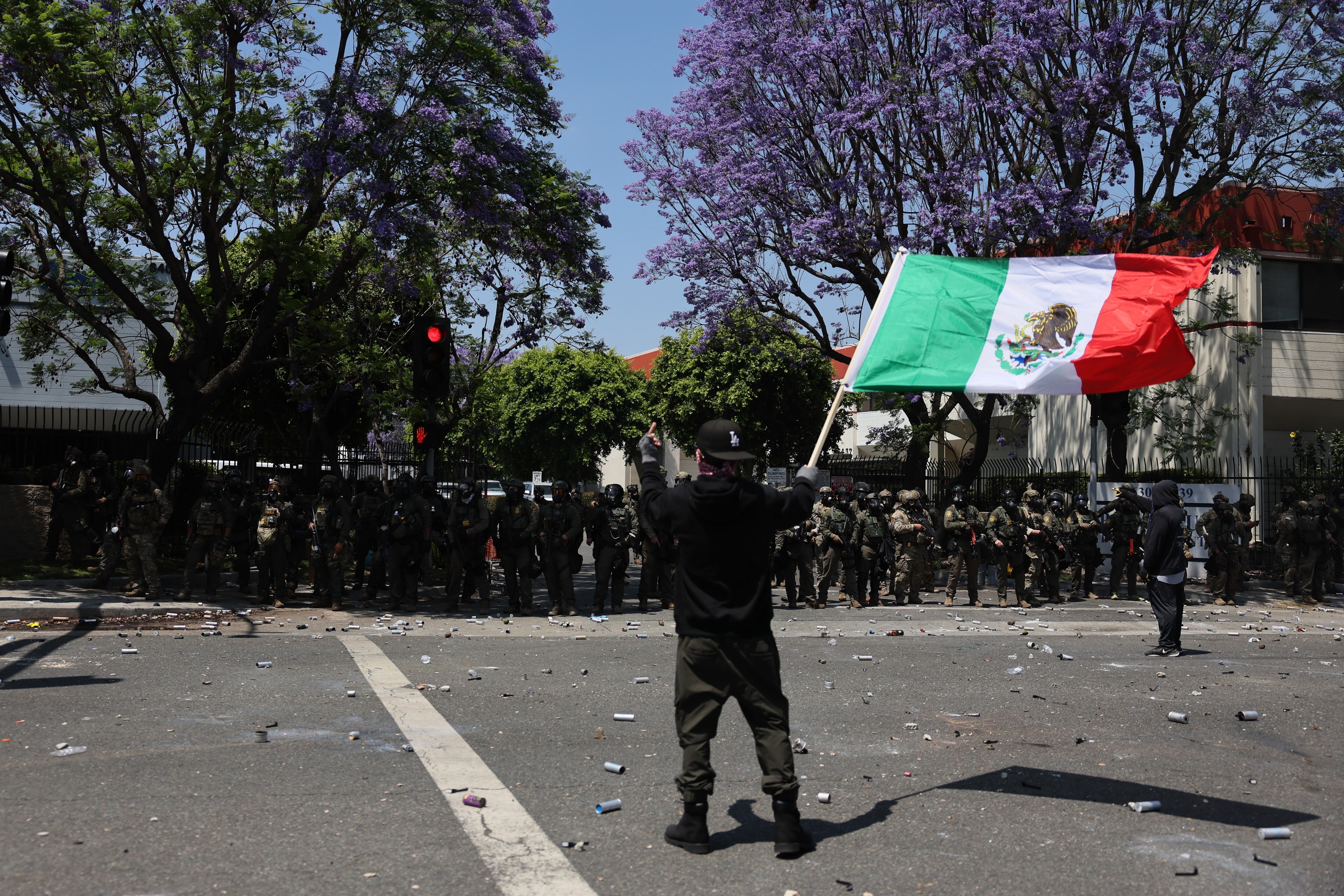 Fotografía del 7 de junio de una manifestante sosteniendo una bandera mexicana durante una protesta contra las redadas del Servicio de Inmigración y Control de Aduanas (ICE) en Paramount (EE.UU.). EFE/ Allison Dinner
