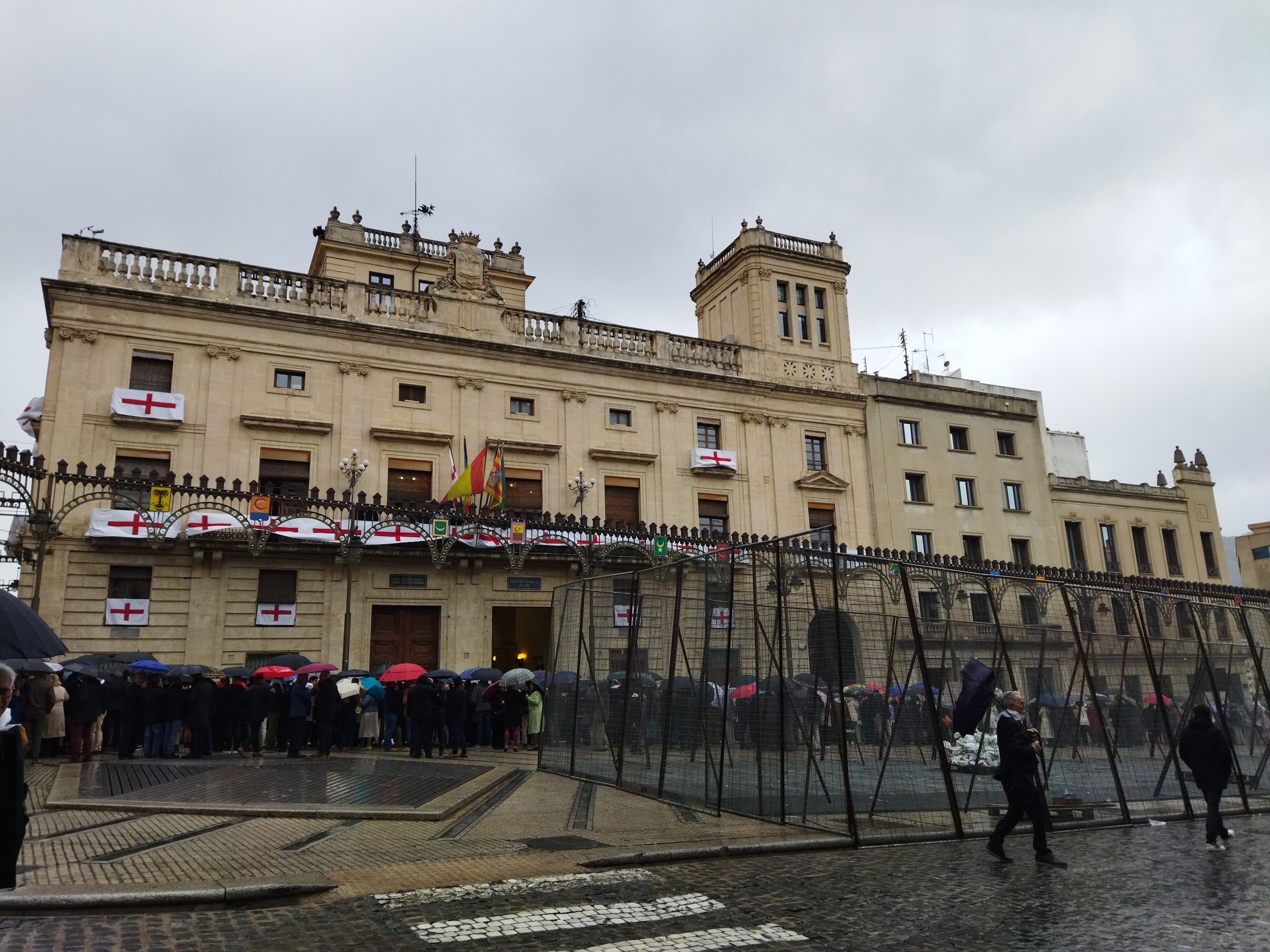 El público esperaba bajo los paraguas a la decisión de la reunión que se estaba celebrando en el Ayuntamiento de Alcoy.