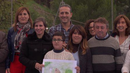 Abrahán posa junto a sus padres, delegada. alcalde y profesores con el dibujo que le ha hecho ganar el primer premio de Andalucía