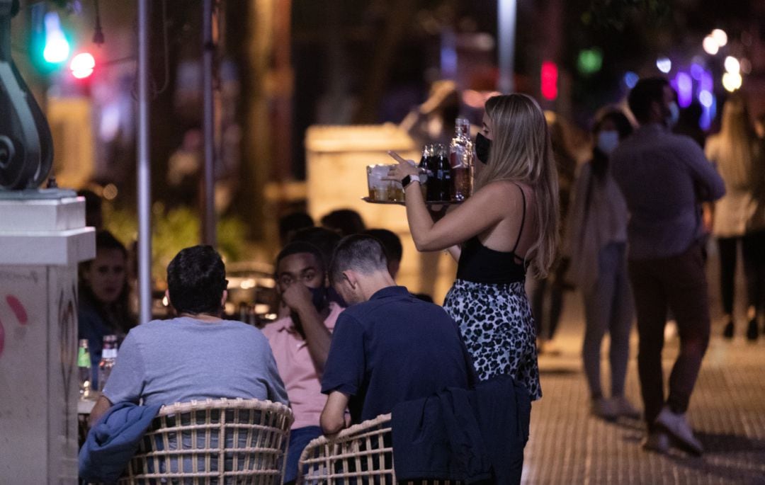 Archivo - Una camarera atiende a varias personas en la terraza de un bar