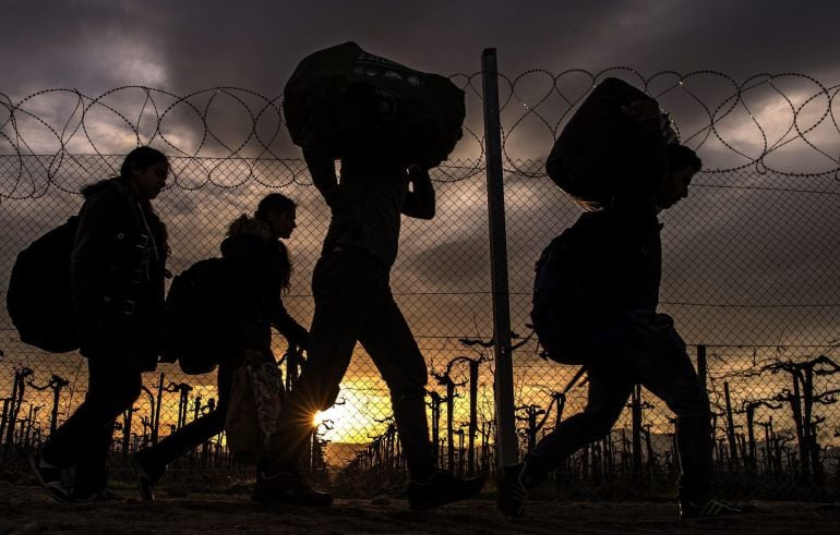 Varias personas cargan con sus enseres en el campo de refugiados de Gevgelija (Macedonia).