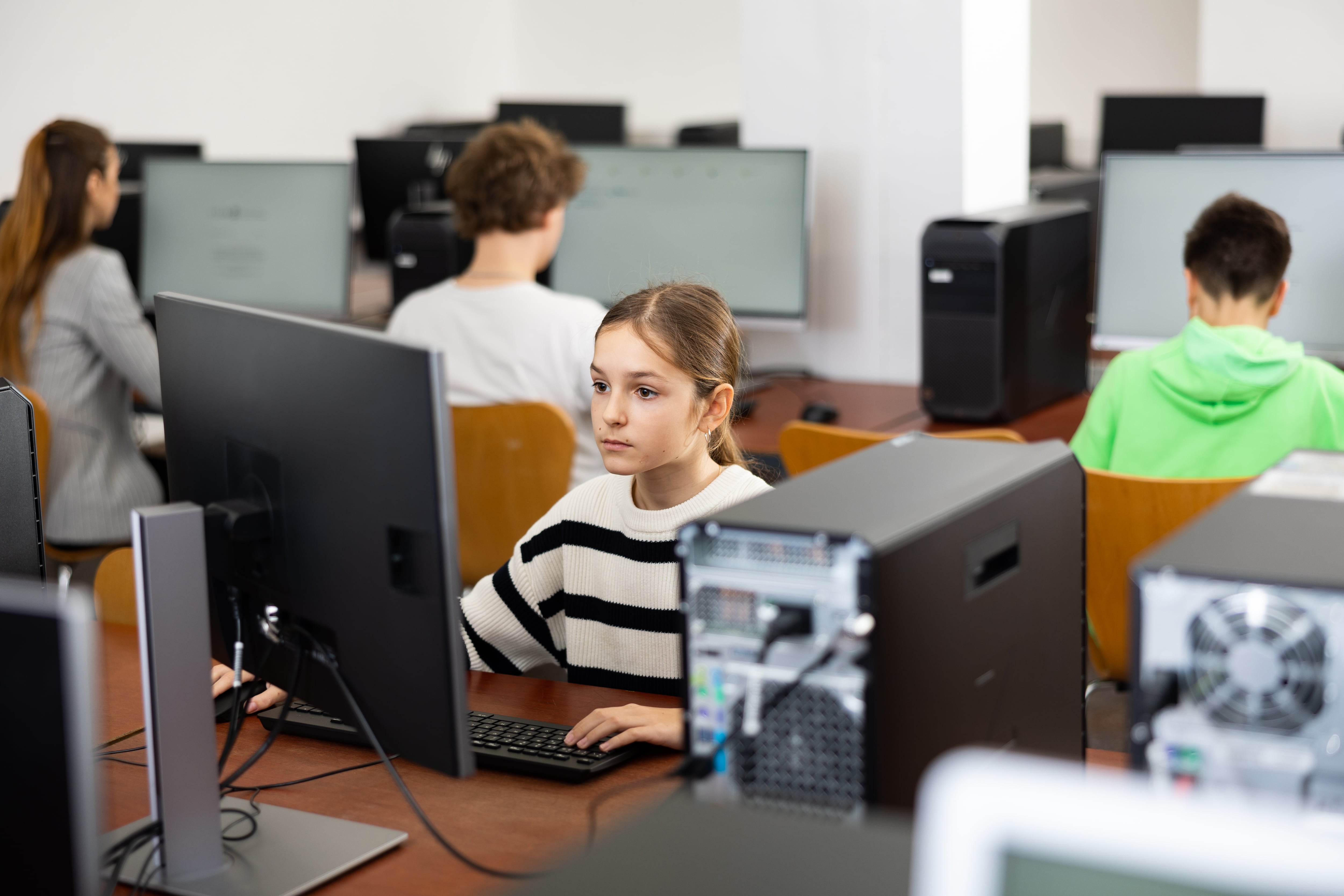 Portrait of female schoolgirl at computers in university computer class