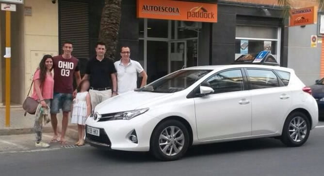 Dos de los alumnos de la autoescuela Paddock posan junto a sus profesores (David, a la derecha).