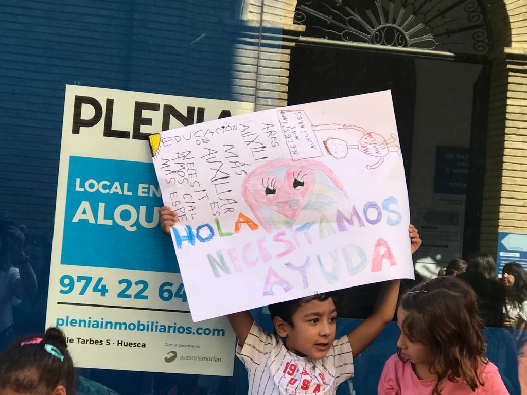 Un niño portando un cartel alusivo a la falta de auxiliares de educación especial