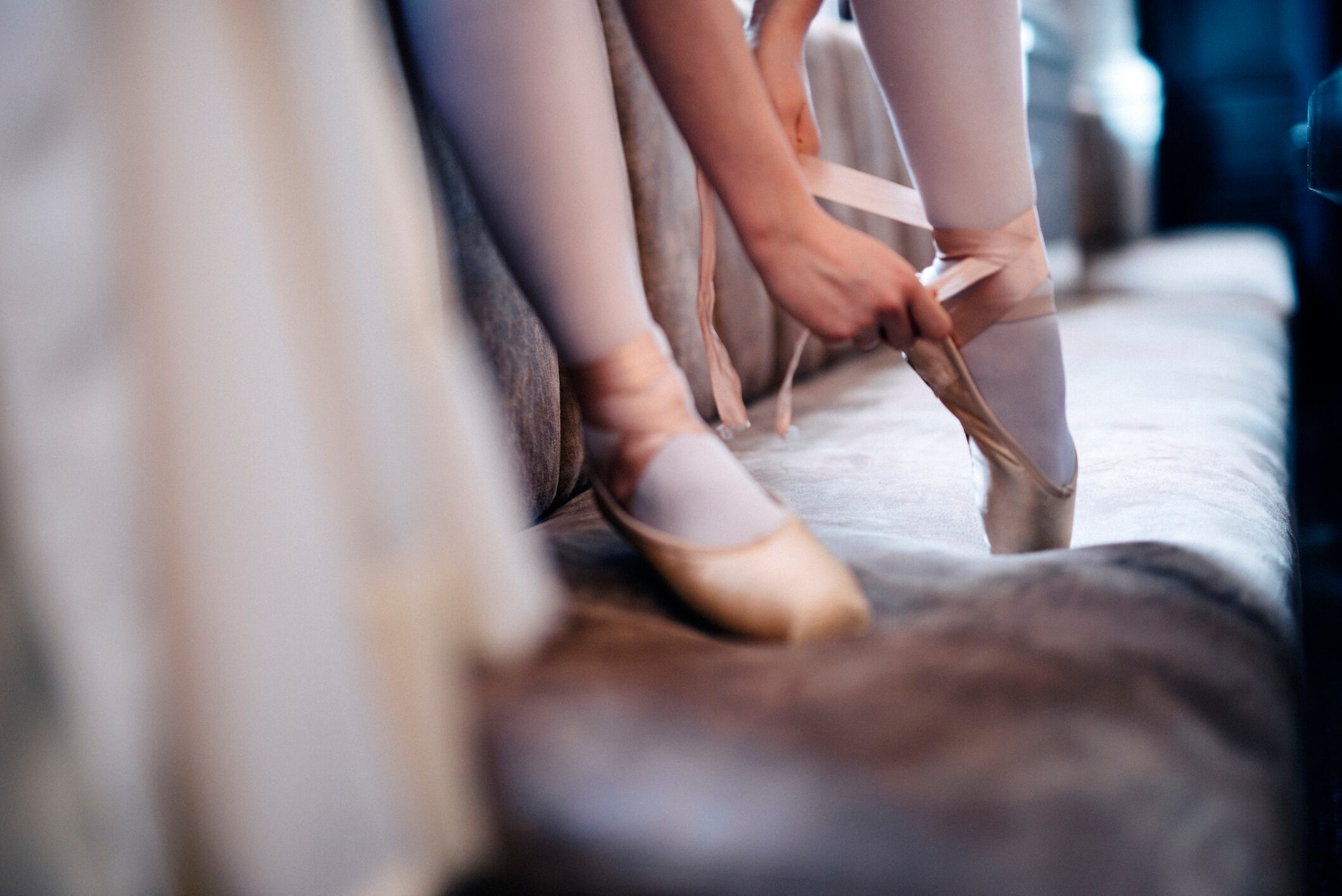 Una mujer se acondiciona sus zapatos de ballet con lazos