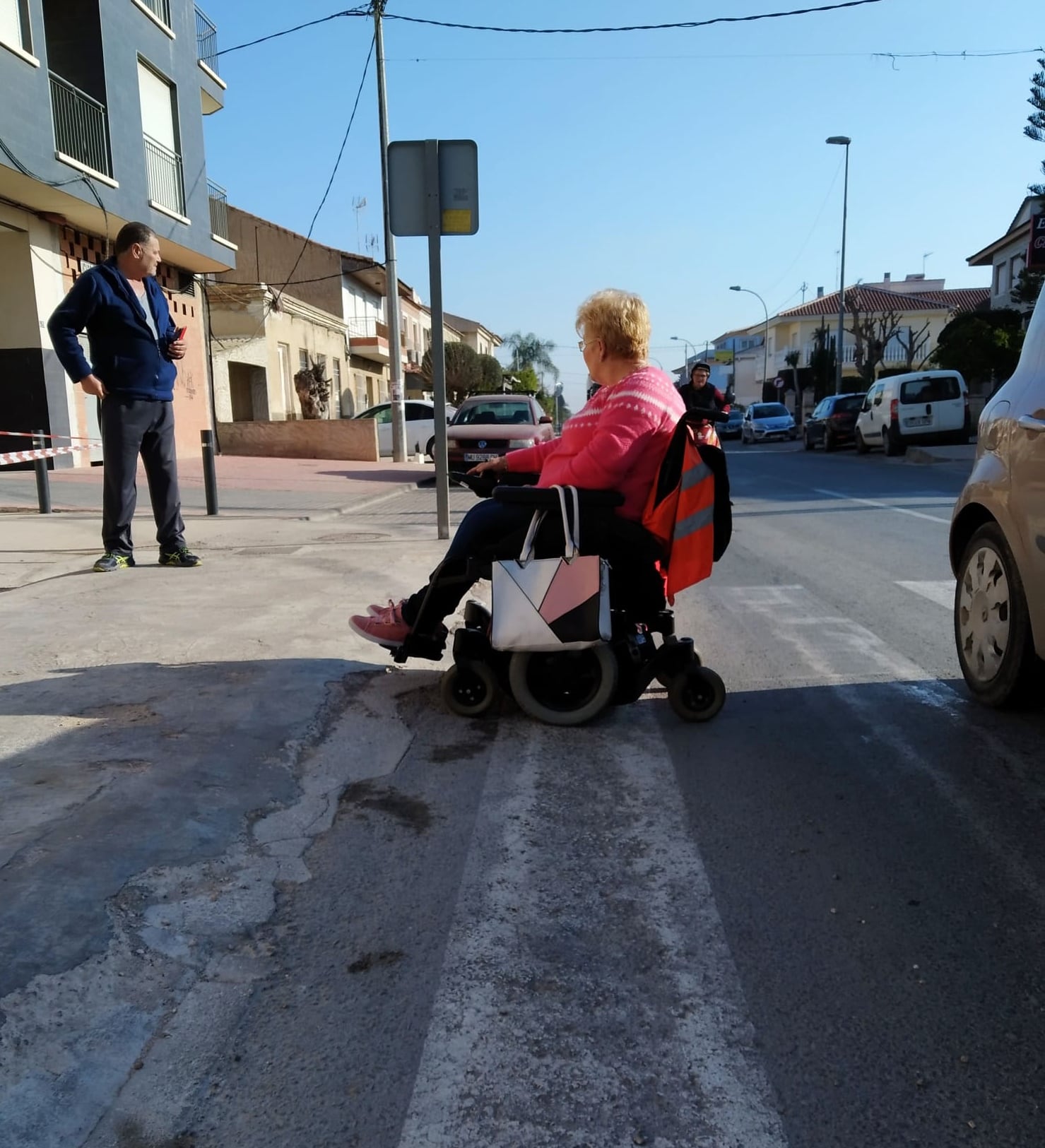 Una vecina en silla de ruedas transita por la calzada en El Raal