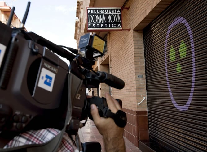 Un reportero gráfico toma imágenes de la fachada de la peluquería de Puzol (Valencia) que regentaba la mujer que fallecida tras ser agredida con un arma blanca por su pareja en el interior del local