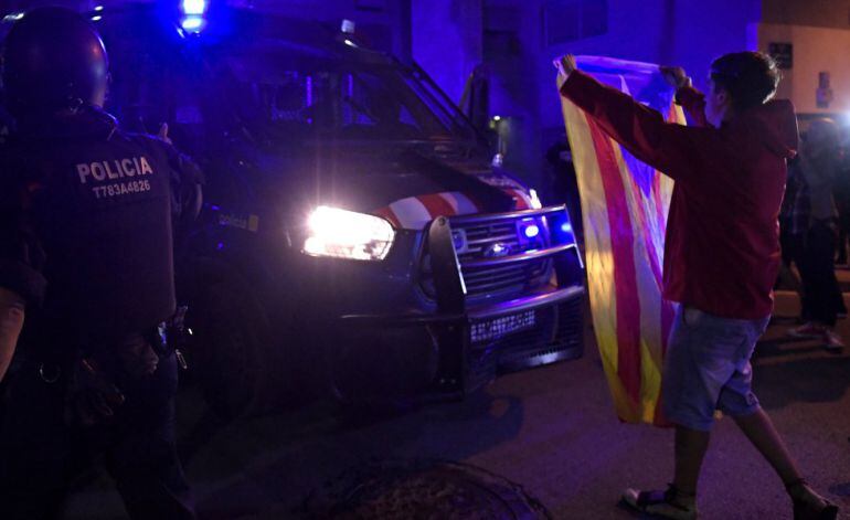 Un joven sostiene una estelada frente a un furgón de los Mossos el 20-S