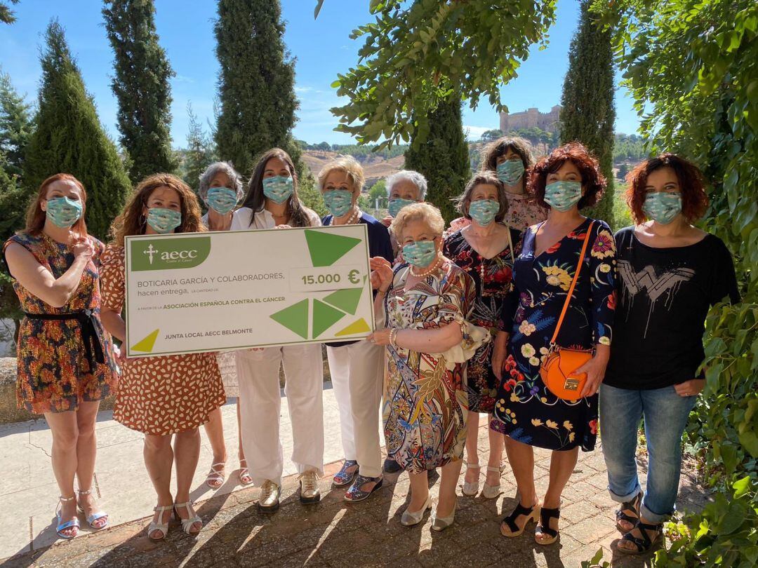 Marián García haciendo entrega, el pasado mes de septiembre, del cheque a las integrantes de la AECC en Belmonte, con el castillo al fondo