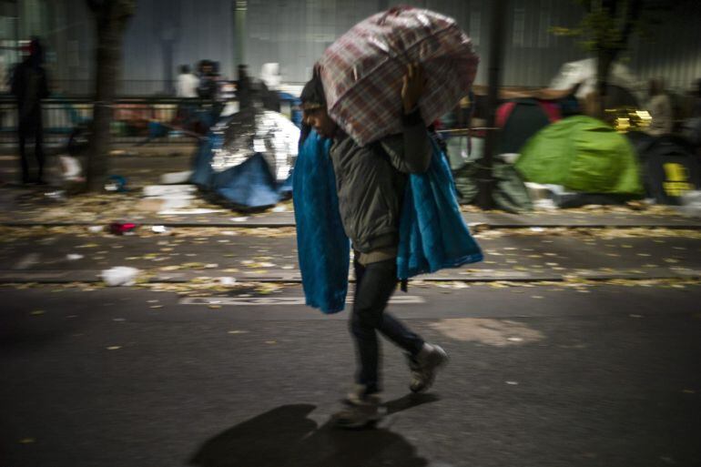 Un refugiado carga con varios enseres.