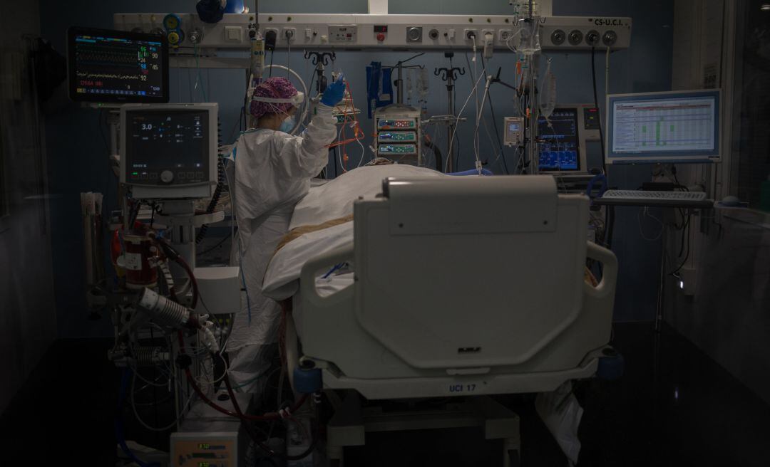 Archivo - Trabajadores sanitarios protegidos atienden a un paciente en la Unidad de Cuidados Intensivos.