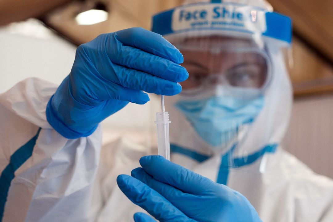 Una trabajadora sanitaria protegida muestra uno de los test de antígenos en imagen de archivo.