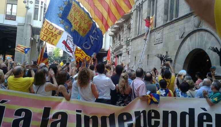 Moment en què una manifestant penja una estelada a la façana de la Paeria