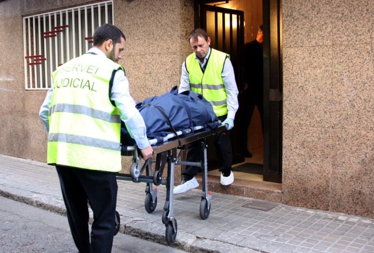 Dos persones del servei judicial retirant el cos d'una de les víctimes al número 18 del carrer Jacint Verdaguer de Premià de Mar
