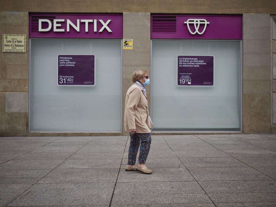 Una mujer pasea delante de una oficina de Dentix