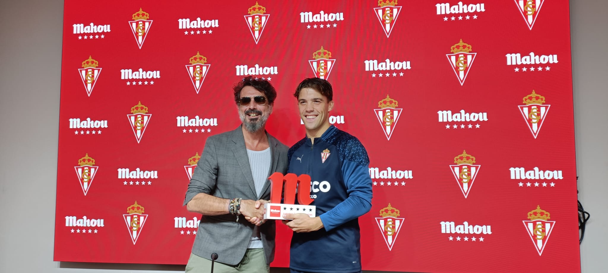 Nacho Méndez recoge el Trofeo Jugador Cinco Estrellas del Sporting del mes de septiembre de manos del encargado del Bambara, Elías Sánchez.