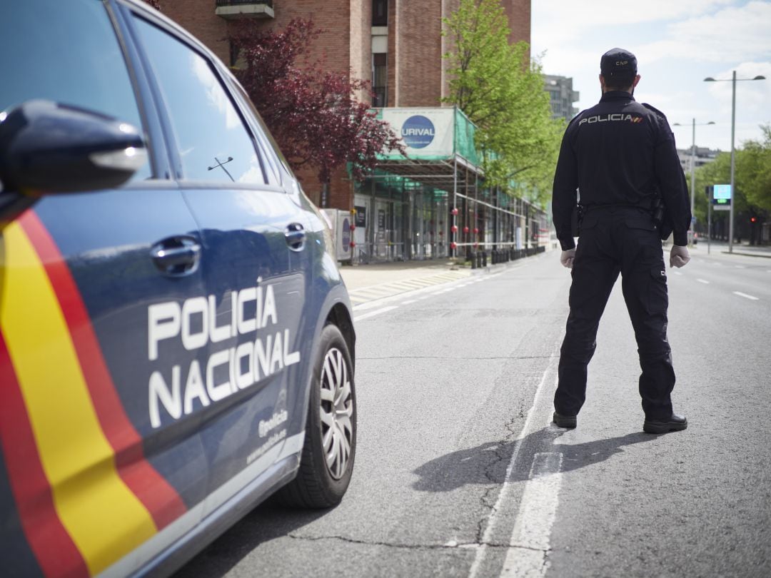 Un policía nacional junto al coche patrulla.