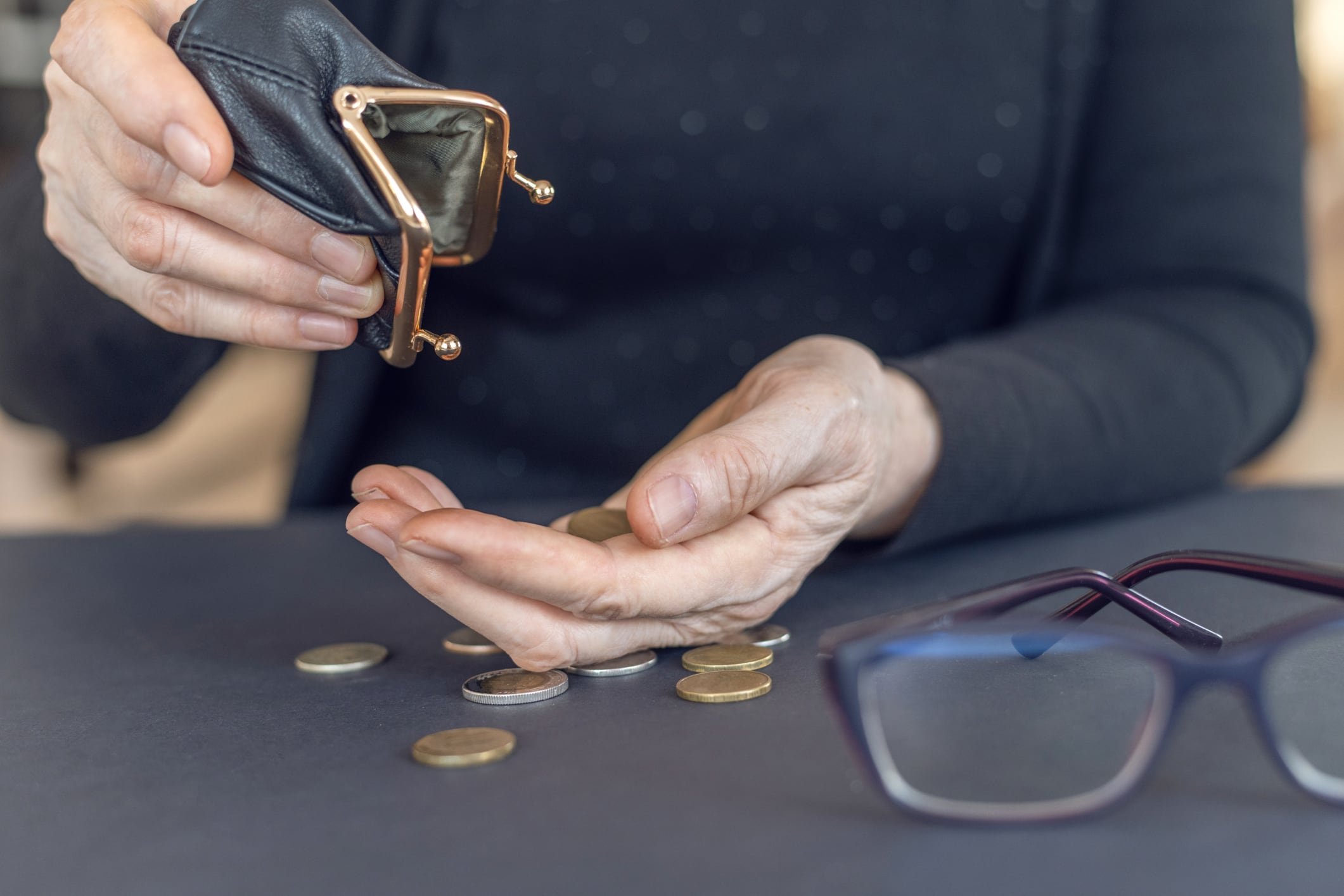 Un anciano busca dinero en su monedero.