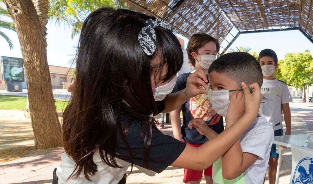 Niños en una escuela de verano se colocan la mascarilla