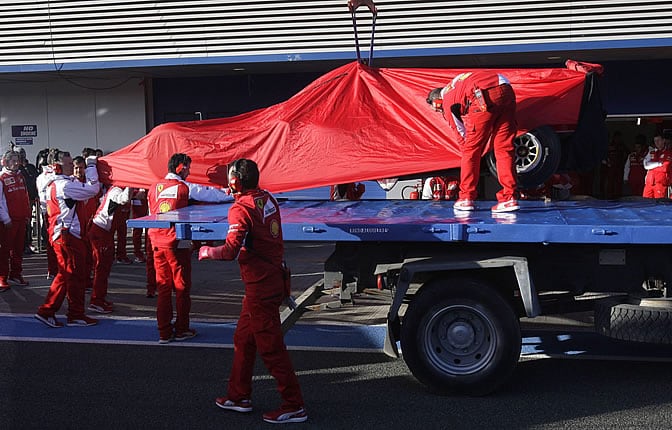 El nuevo monoplaza F14T, pilotado por el finlandés Kimi Raikkonen, es izado sobre un camión grúa tras una avería durante la primera jornada de ensayos de pretemporada