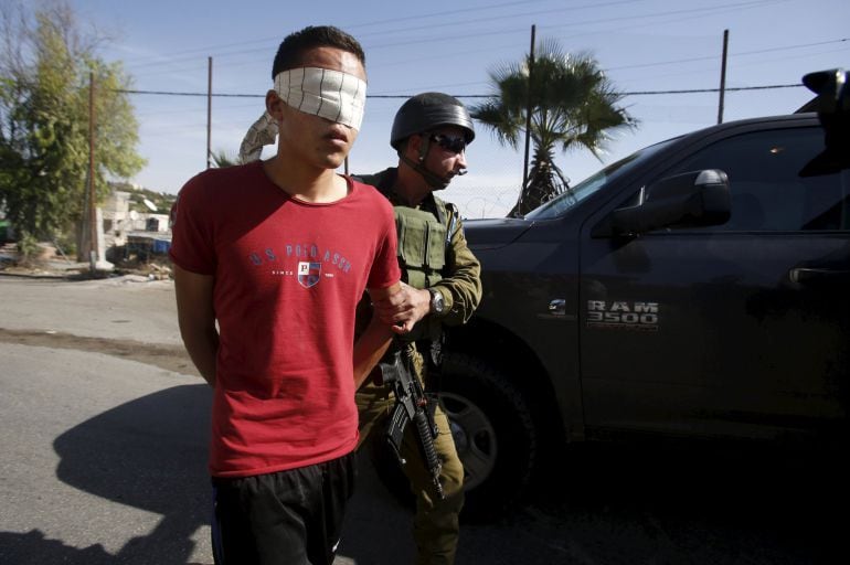 Un soldado de Israel lleva con los ojos vendados a un detenido palestino.