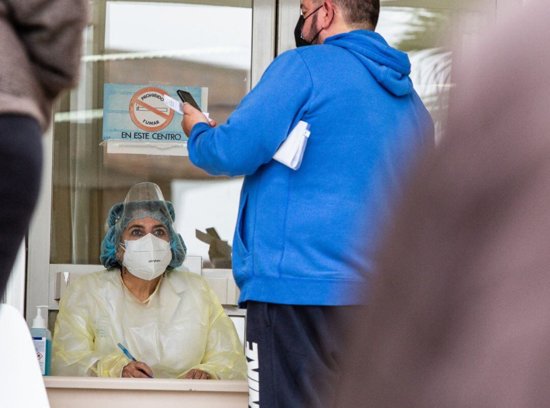 Un hombre habla con una sanitaria en la fila frente al Centro de Salud La Paz, en Badajoz, Extremadura (España), a 26 de enero de 2021. El Servicio Extremeño de Salud (SES) ha organizado en las 9 zonas de salud de Badajoz cribados masivos para detectar positivos por coronavirus que sean asintomáticos. La pasada semana se empezó por la Zona de Salud de El Progreso, y esta semana se harán en Valdepasillas, Cerro Gordo, Ciudad Jardín, La Paz y Suerte de Saavedra, San Fernando, San Roque y Zona Centro, 
 