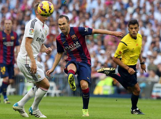 El centrocampista del FC Barcelona Andrés Iniesta golpea el balón ante el centrocampista alemán del Real Madrid Toni Kroos.