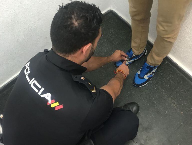 Un policía retira la cámara de las zapatillas con la que el detenido grababa a las clientas de un establecimiento comercial