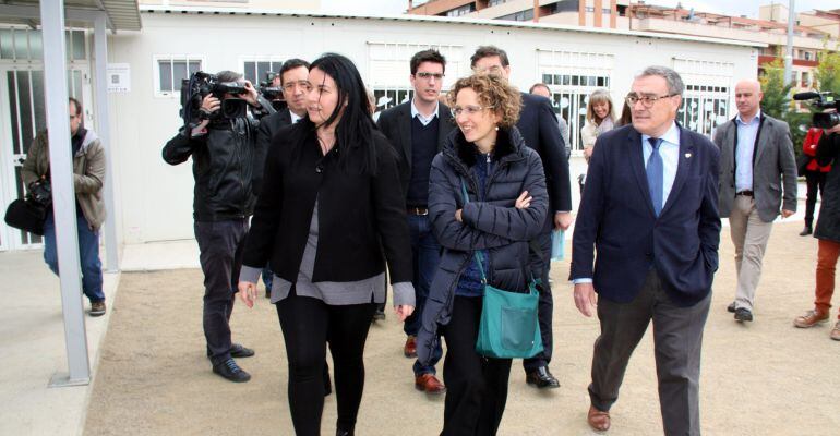 La consellera d'Ensenyament, Meritxell Ruiz, entre l'alcalde de Lleida, Àngel Ros, i la directora de l'escola Pinyana caminant per l'exterior del centre fet de mòduls prefabricats