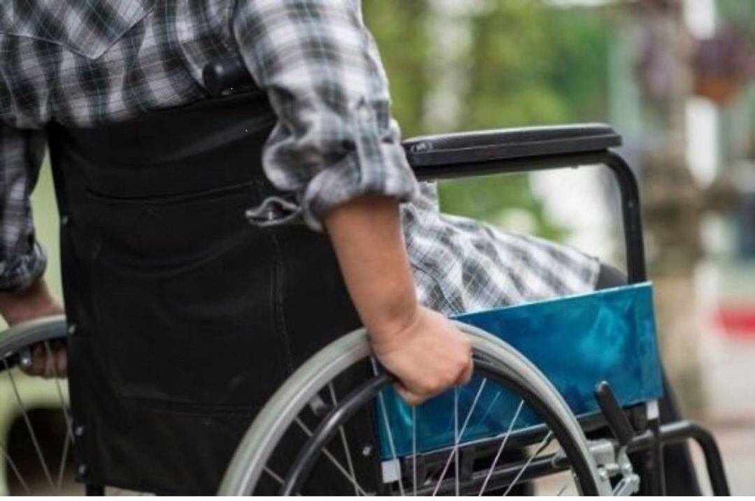 Un hombre en silla de ruedas sale a la calle.
