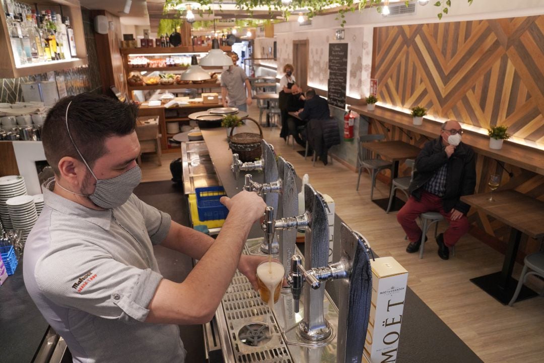 Archivo - Un camarero llena un vaso de cerveza en un restaurante