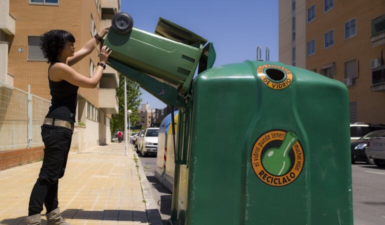 Una joven depositando vidrio en uno de los contenedores.