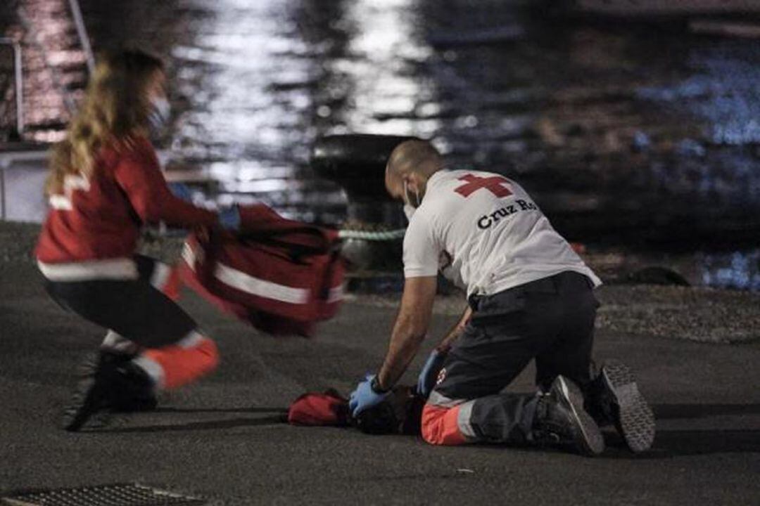 Sanitarios, voluntarios de la Cruz Roja y marineros de Salvamento reaniman sobre el suelo del puerto de Arguineguín a un niño pequeño que desembarcó de la patera localizada al sur de Gran Canaria con hipotermia severa.