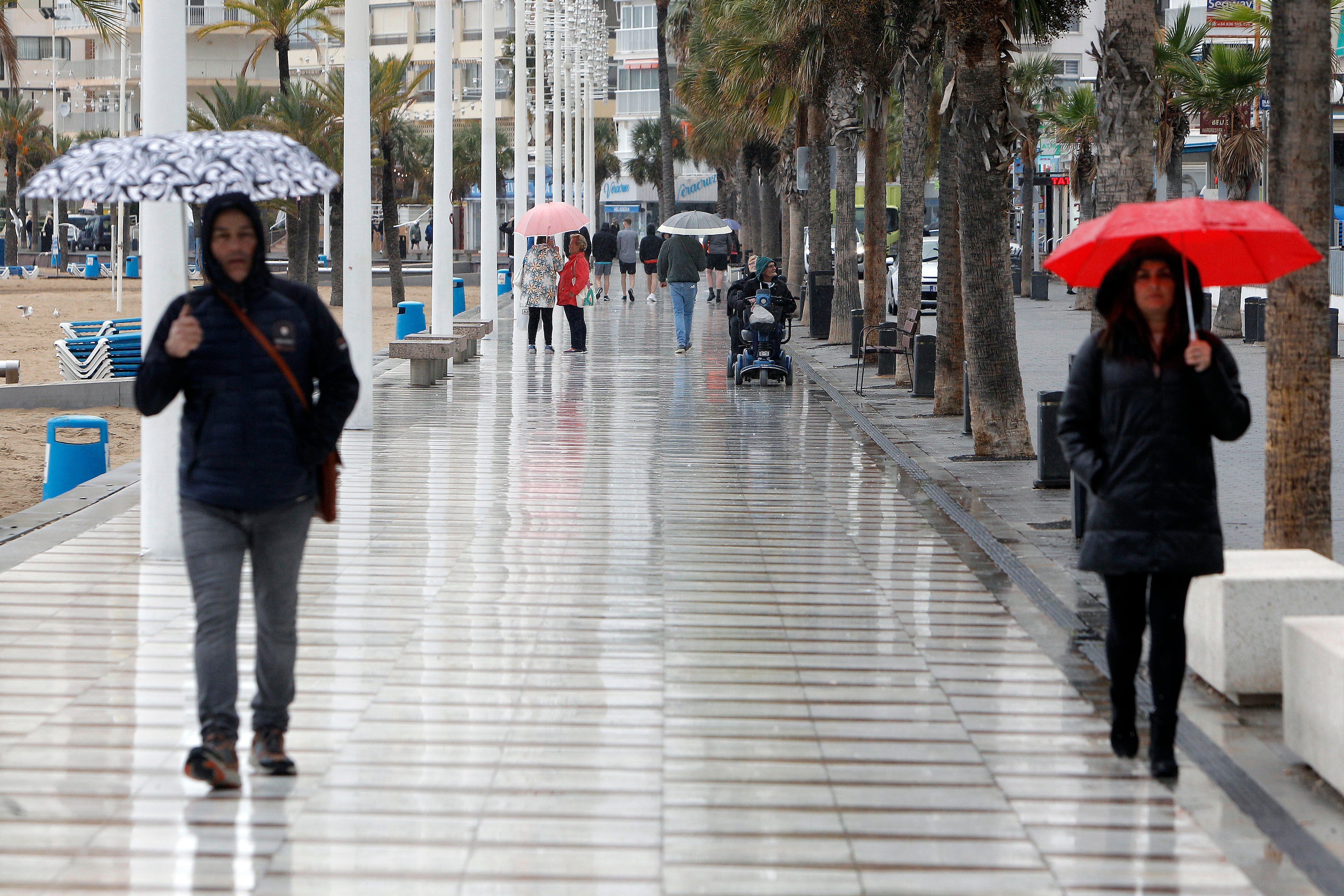 Peatones bajo la lluvia en un paseo de Benidorm. EFE/ Morell