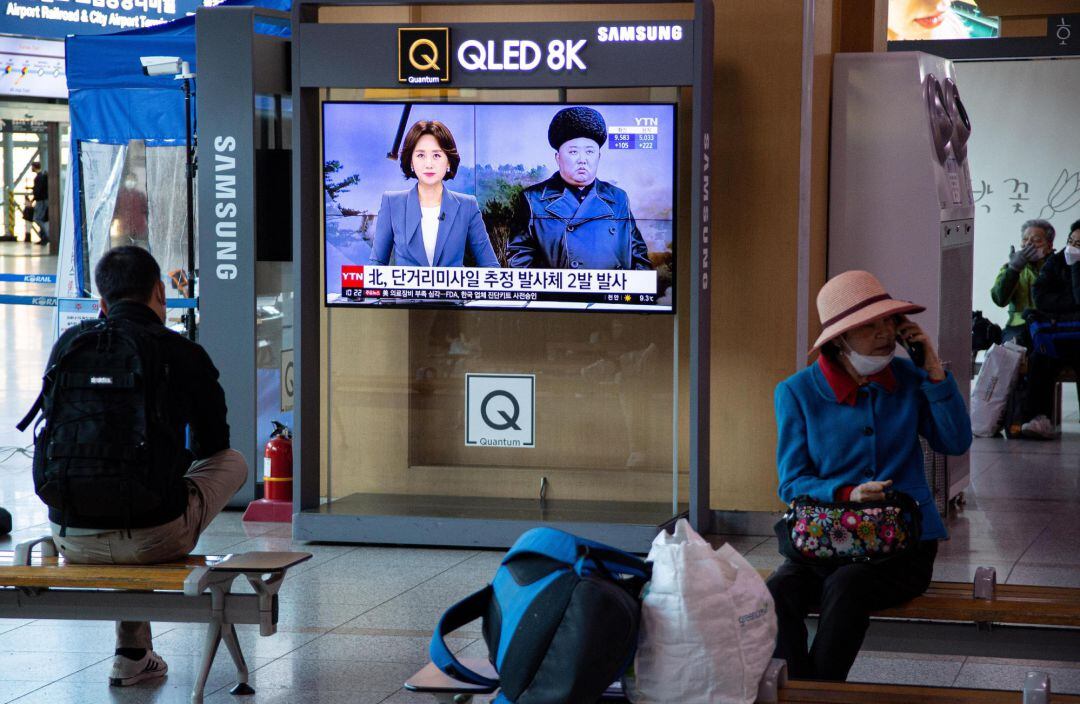 En Corea del Norte, ciudadanos esperando transporte en una estación de Seúl mientras la televisión anuncia un nuevo lanzamiento prueba de misiles. Corea del Norte no ha reportado ningún caso de Covid19. es uno de los 19 países que dicen estar libres de la pandemia 