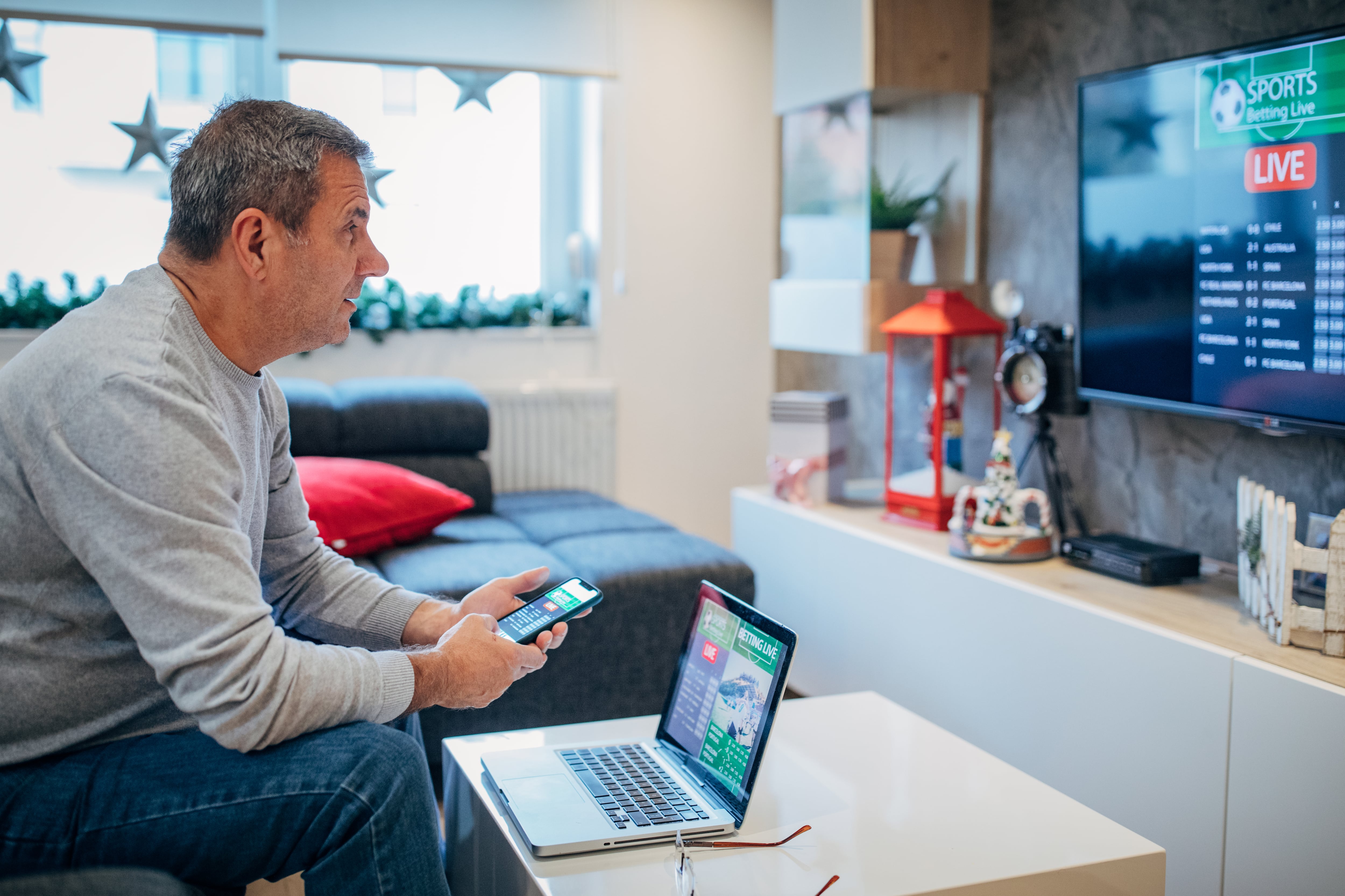 Senior man watches soccer game and bets in his living room