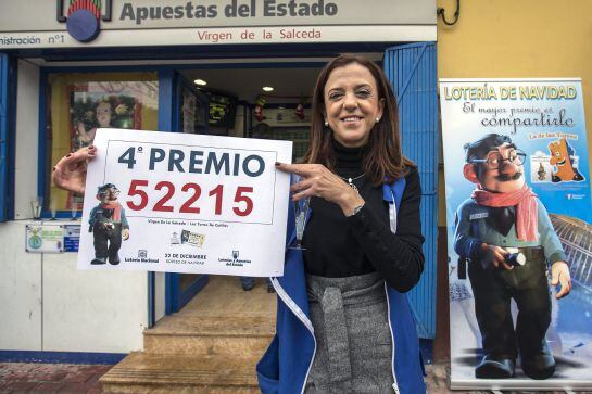 La propietaria de la administración número uno de las Torres de Cotillas (Murcia) Fuensanta Ortíz, muestra el cartel con el cuarto premio de la loteria de Navidad, el 52215, del que han vendido 15O décimos.