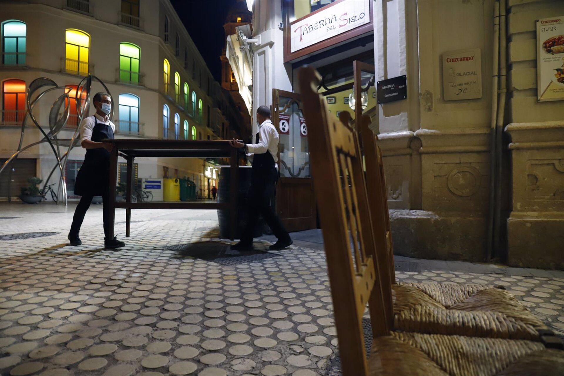 Dos camareros recogen la terraza de un bar en el centro de Málaga
