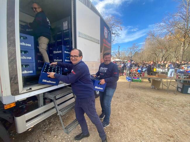 Rebollo, Cubero y otros voluntarios descargando cajas de botellines