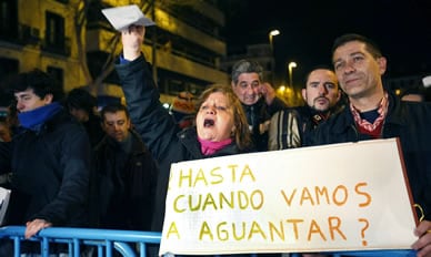 Varias personas muestran pancartas durante una concentración en la que varios centenares de asistentes han protestado contra la corrupción en la sede del PP en Madrid.