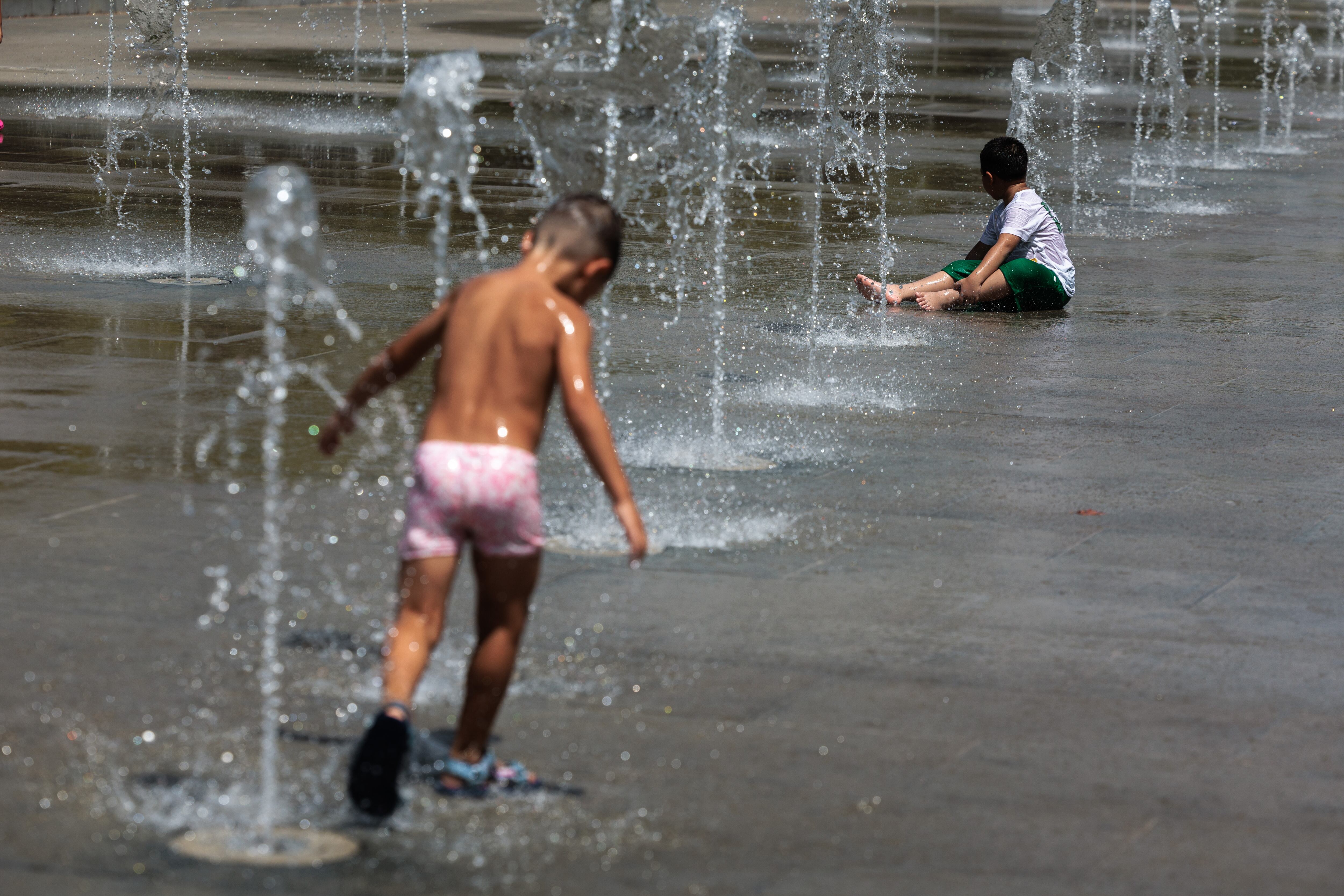 Unos niños se refrescan en una fuente EFE/Biel Aliño