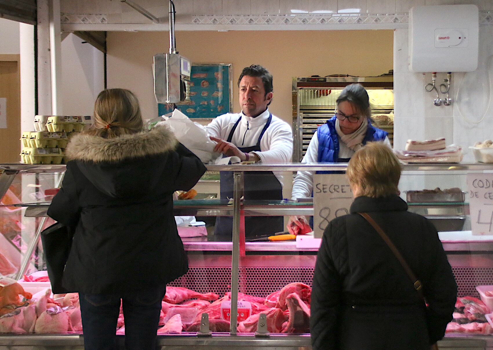 Un vendedor del mercado de abastos atienda a un par de clientes