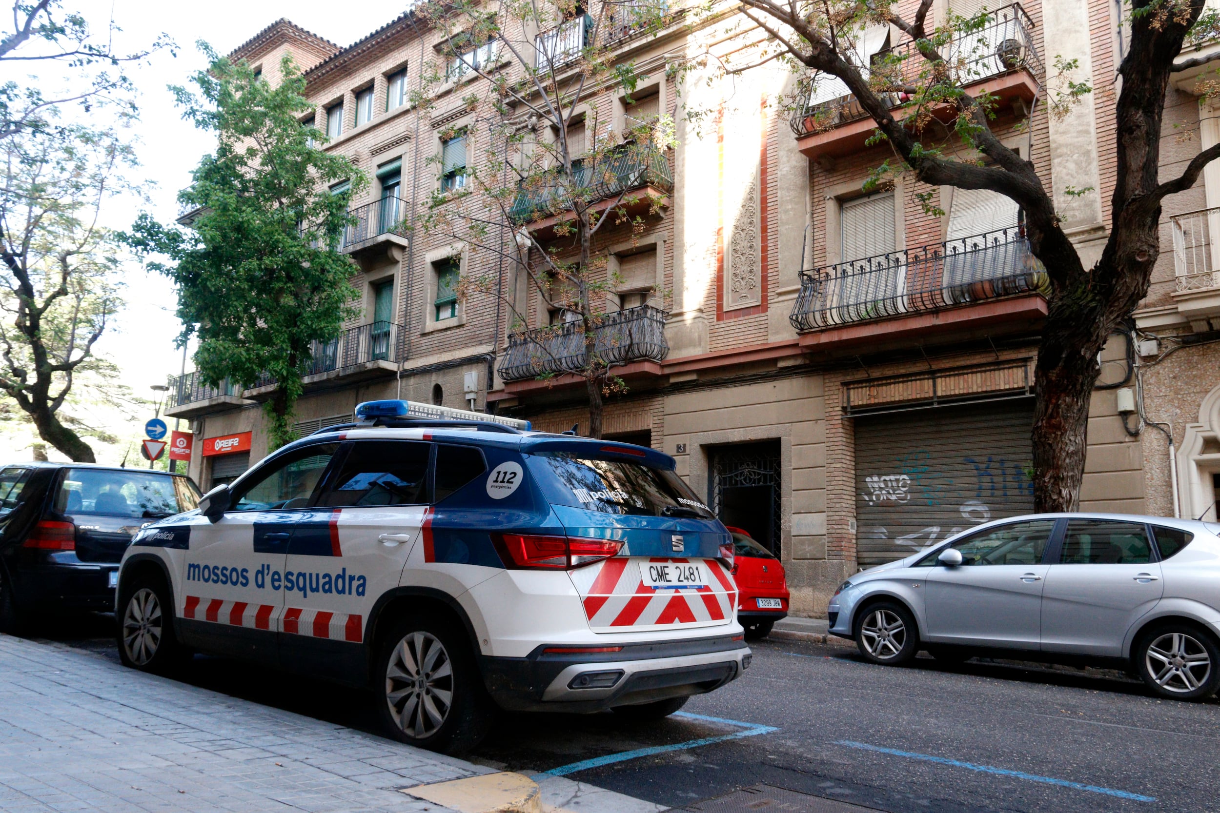 Un vehicle dels mossos aparcat al davant de l'edifici del carrer Valentí Almirall on van passar els fets. Foto: ACN.