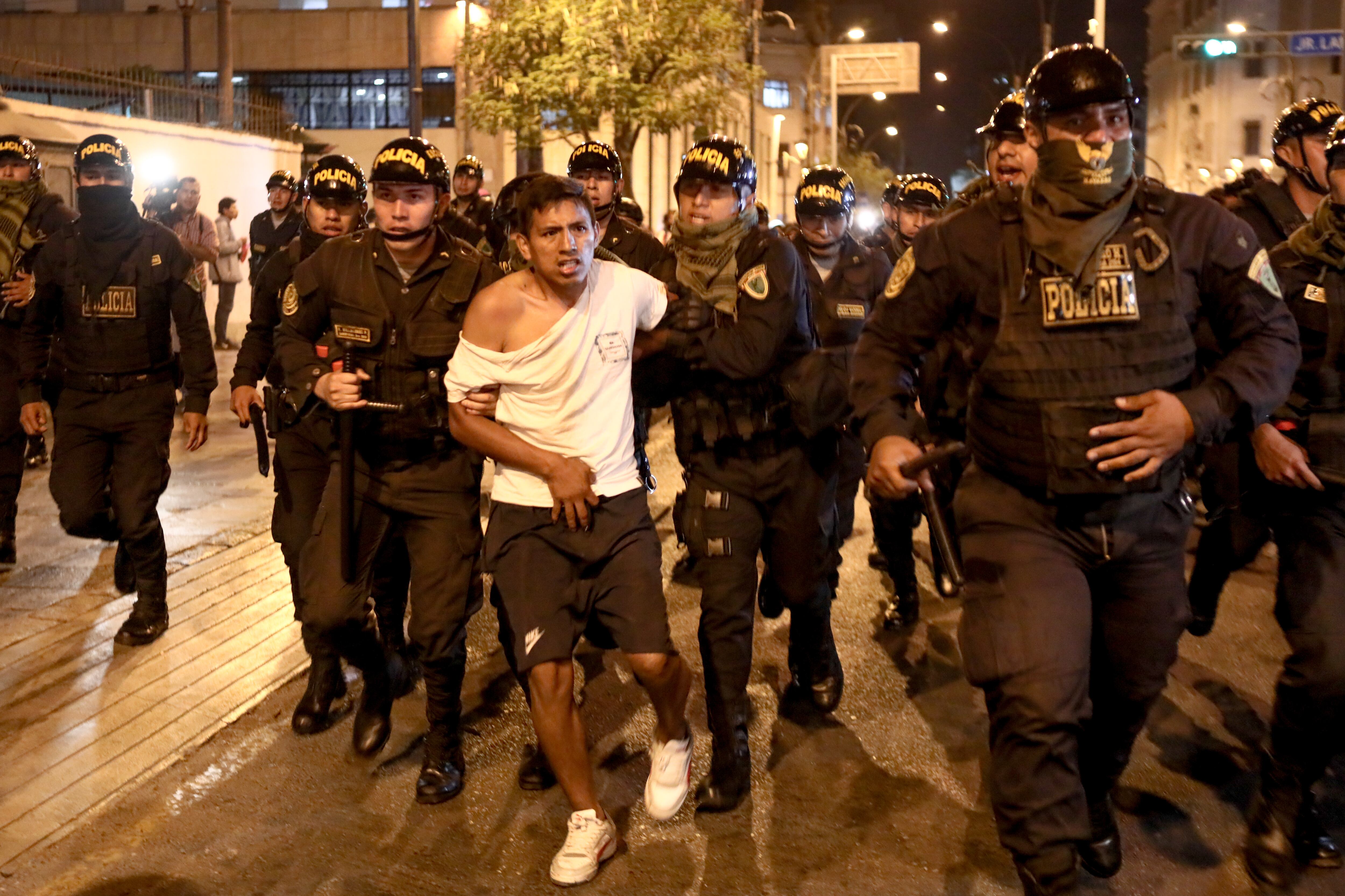 Un manifestante es retenido por la policía peruana durante las protestas que piden un adelanto electoral