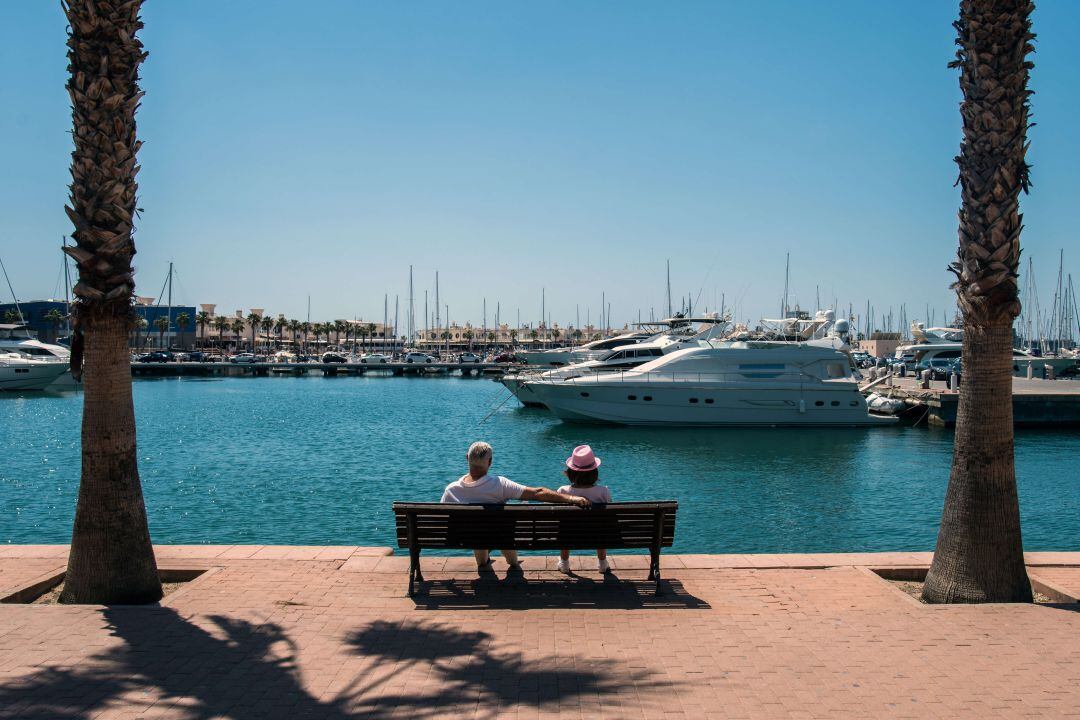 Dos turistas descansan en un banco del paseo de Conde Vallellano