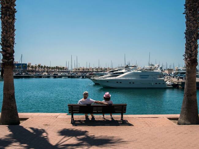 Dos turistas descansan en un banco del paseo de Conde Vallellano