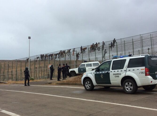 Fotografía de la valla de Melilla en la que se pueden ver los inmigrantes encaramados en la zona superior