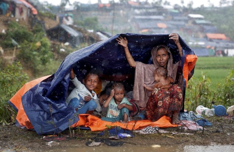 Refugiados Rohingya se refugian de la lluvia en un campo de Bangladesh.