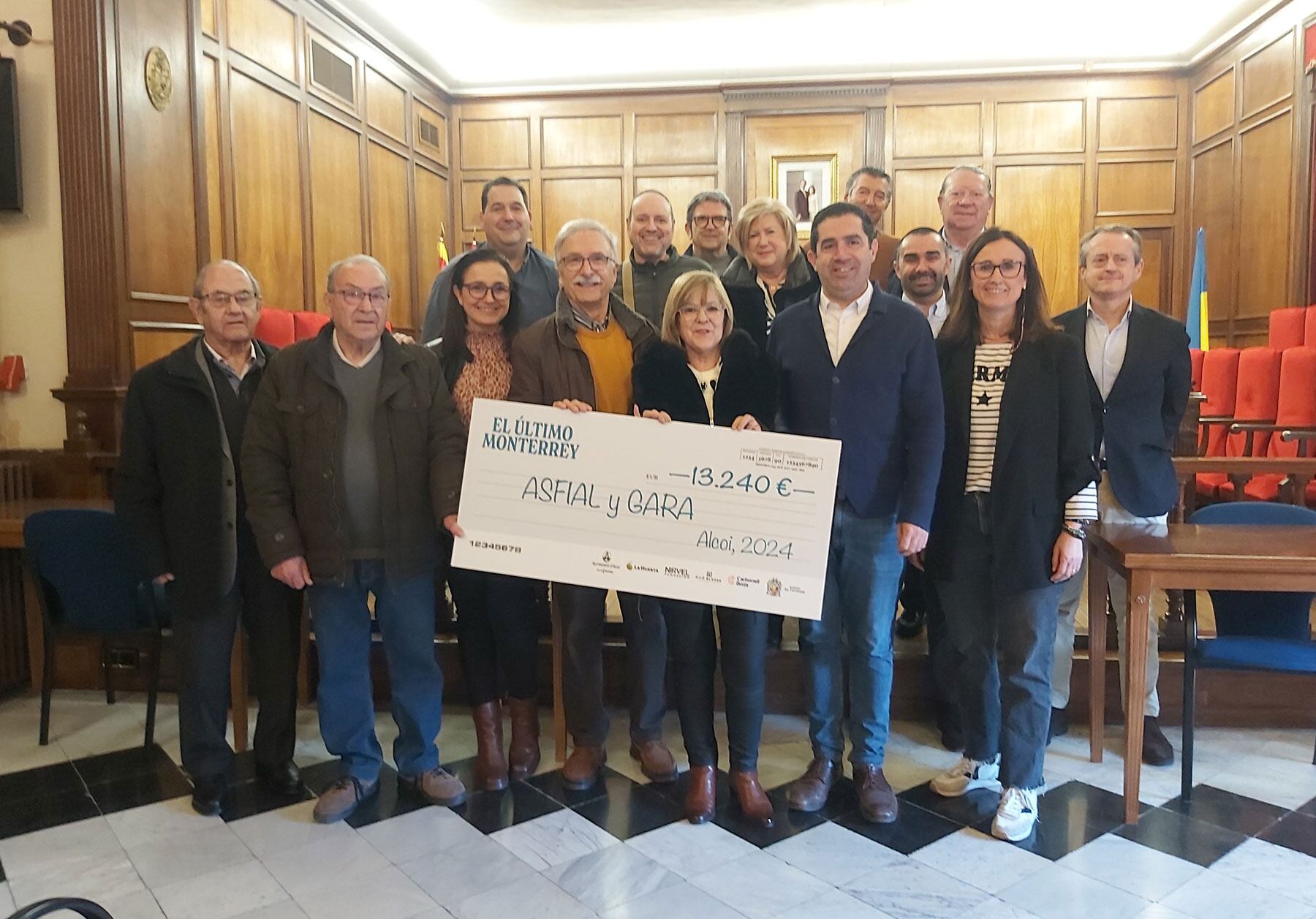 Foto de familia con el cheque y los asistentes al acto que tuvo lugar en el salón de plenos del Ayuntamiento