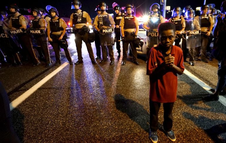 Amarion Allen, 11-years-old stands in front of a police line shortly before shots were fired in a police-officer involved shooting in Ferguson, Missouri August 9, 2015.  Two people were shot in the midst of a late-night confrontation between riot police a